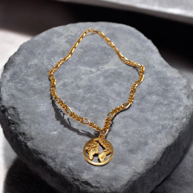 طوق ذهبي بقلادة خريطة العالم مفرغة فوق حجر رخامي رمادي