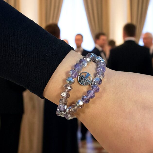 أسوارة كريستال بنفسجية بقلادة فضية تظهر على معصم يد عارضة في قاعة احتفالات