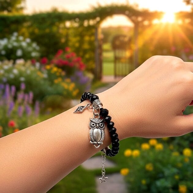 أسوارة خرز أسود بقلادة بومة فضية على يد امرأة في حديقة