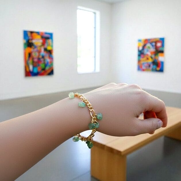 أسوارة ذهبية بقلادات أحجار خضراء طبيعية على معصم امرأة