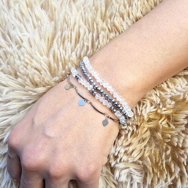 طقم أساور خرز كريستال شفاف وفضي مع قلادات قلوب على معصم امرأة