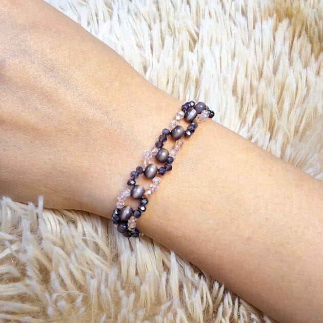 أسوارة خرز كريستال رمادي ووردي بتصميم حلقات مفرغة على معصم امرأة