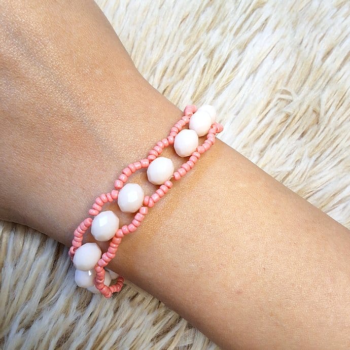 أسوارة خرز أبيض ووردي بتصميم حلقات مفرغة على معصم امرأة