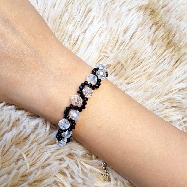 أسوارة خرز كريستال أسود وشفاف بتصميم هندسي على معصم امرأة