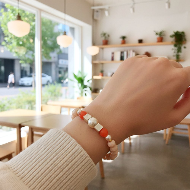 أسوارة خرز مضلع وكريستال برتقالي مضلع مع لؤلؤة بالمنتصف على معصم عارضة