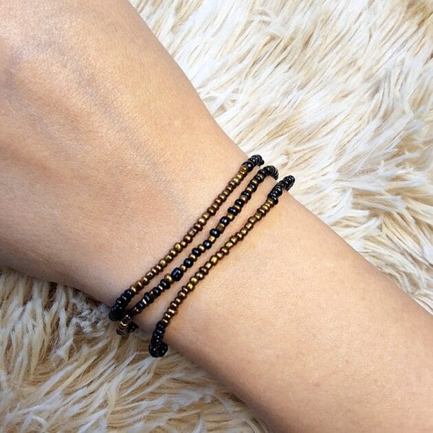 أسوارة نول خرز مبرومة باللون الذهبي والأسود على معصم امرأة