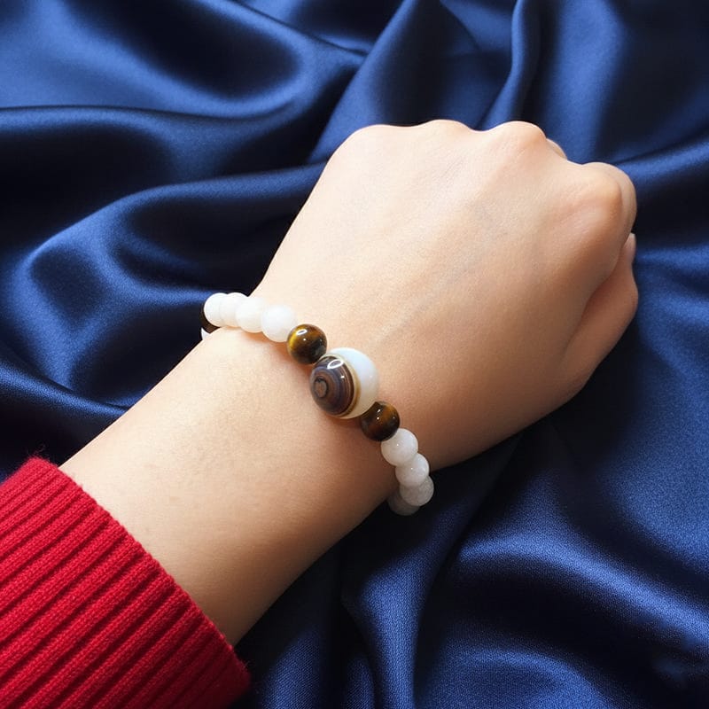 أسوارة خرز أحجار قمر بيضاء وحجر عقيق مخطط على معصم امرأة