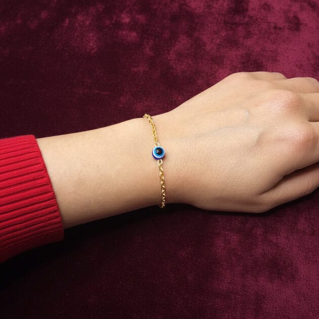 أسوارة ذهبية ناعمة بقلادة عين زرقاء على معصم امرأة