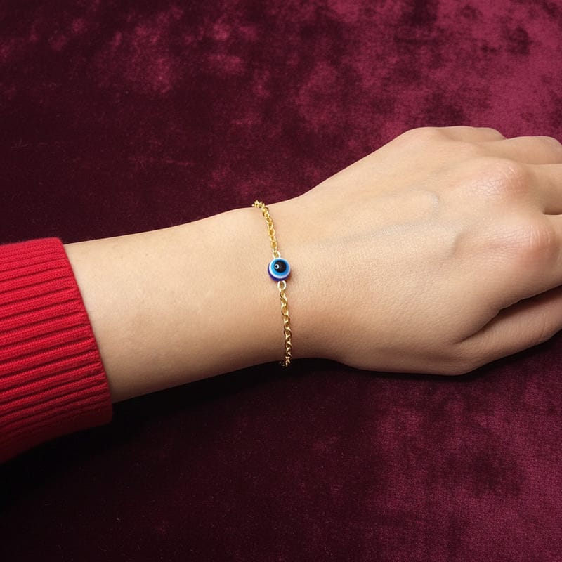 أسوارة ذهبية ناعمة بقلادة عين زرقاء على معصم امرأة