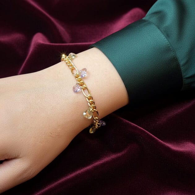 أسوارة ذهبية بقلادات أحجار كريستال شفافة على معصم امرأة