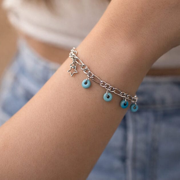 أسوارة فضية بخرز فيروزي ونجمة مفرغة على معصم امرأة ترتدي جينز