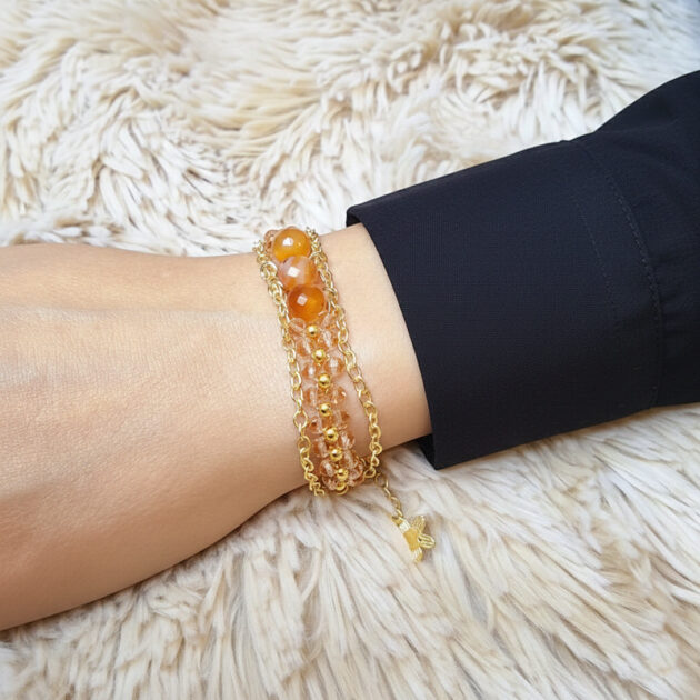 أسوارة ذهبية عريضة بأحجار عقيق وكريستال على معصم امرأة