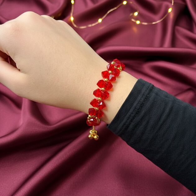 أسوارة خرز أحمر لامع مع تفاصيل ذهبية على المعصم