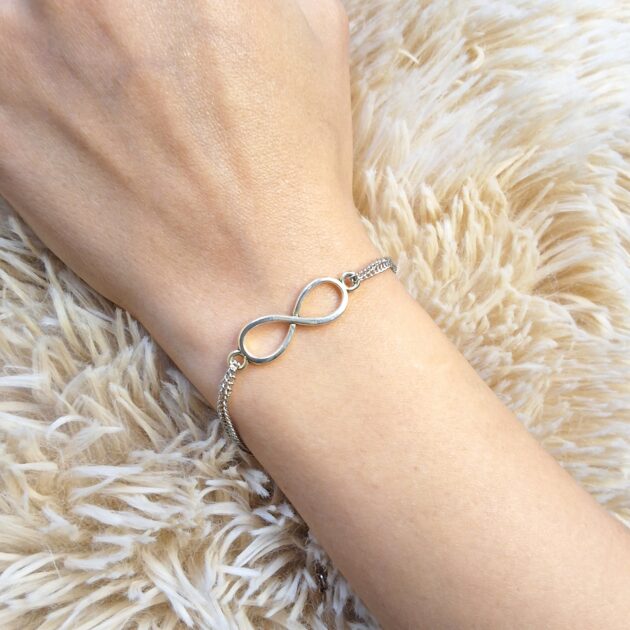 أسوارة سلسلة فضية رقيقة برمز اللانهاية على معصم امرأة
