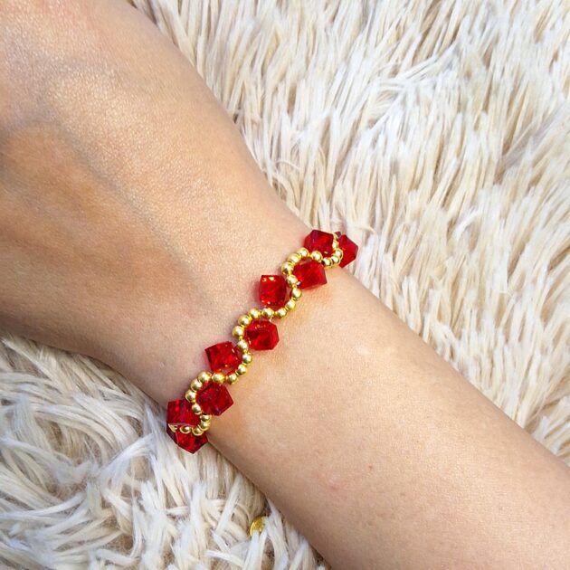 أسوارة خرز كريستال أحمر مكعب مع خرز ذهبي على معصم امرأة
