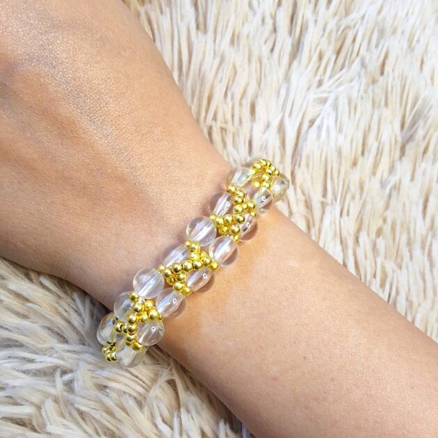 أسوارة خرز كريستال شفاف وذهبي بتصميم حلقات مفرغة على معصم امرأة