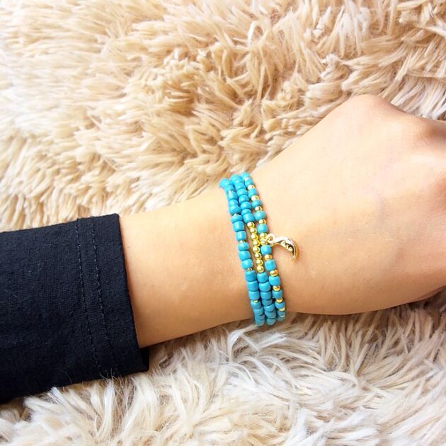 أسوارة خرز فيروزي بقلادة هلال ذهبية على معصم امرأة