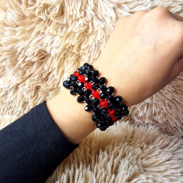 أسوارة عريضة من الكريستال الأسود بوسط أحمر على معصم امرأة