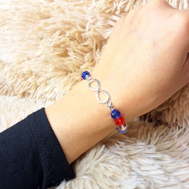 أسوارة خرز كريستال ملون بقلادة Infinity فضية على معصم امرأة