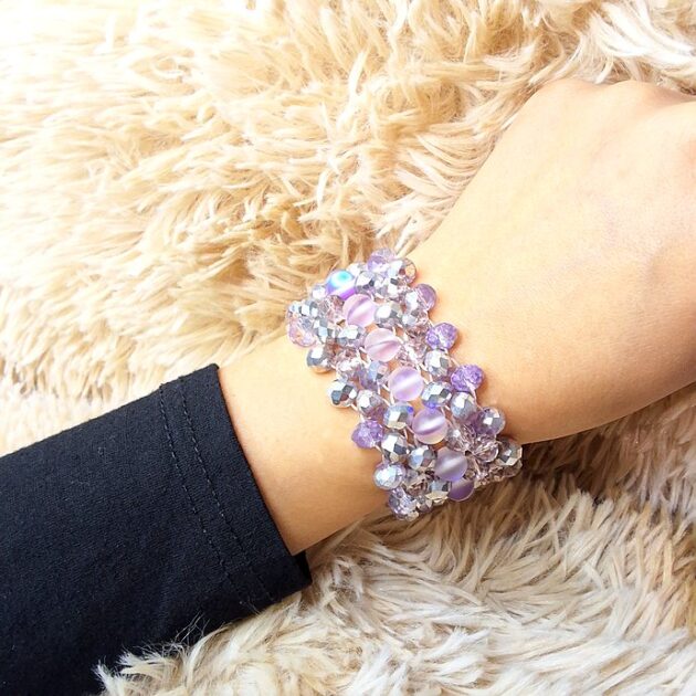 أسوارة عريضة من الكريستال البنفسجي والرمادي المضلع على معصم امرأة