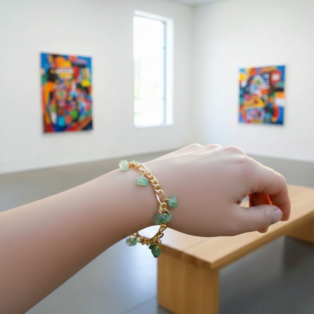 أسوارة ذهبية بقلادات أحجار خضراء طبيعية على معصم امرأة