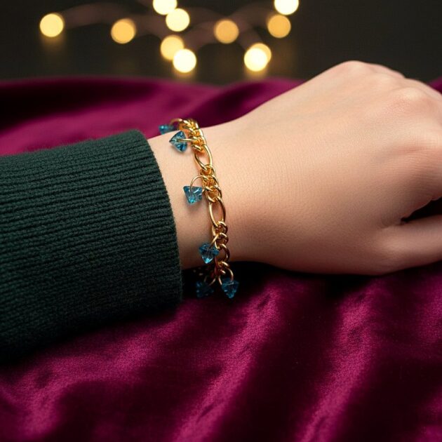 أسوارة ذهبية بقلادات كريستال أزرق هرمية على معصم امرأة