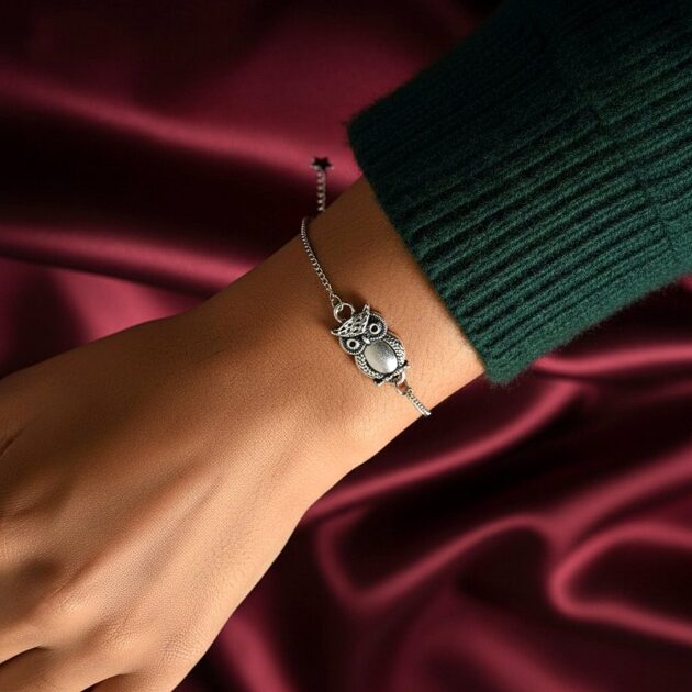 أسوارة فضية بقلادة بومة مفرغة على معصم امرأة