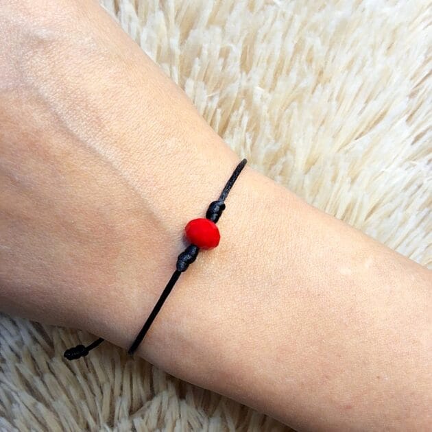 أسوارة خيط سوداء بحجر أحمر بتصميم بسيط.