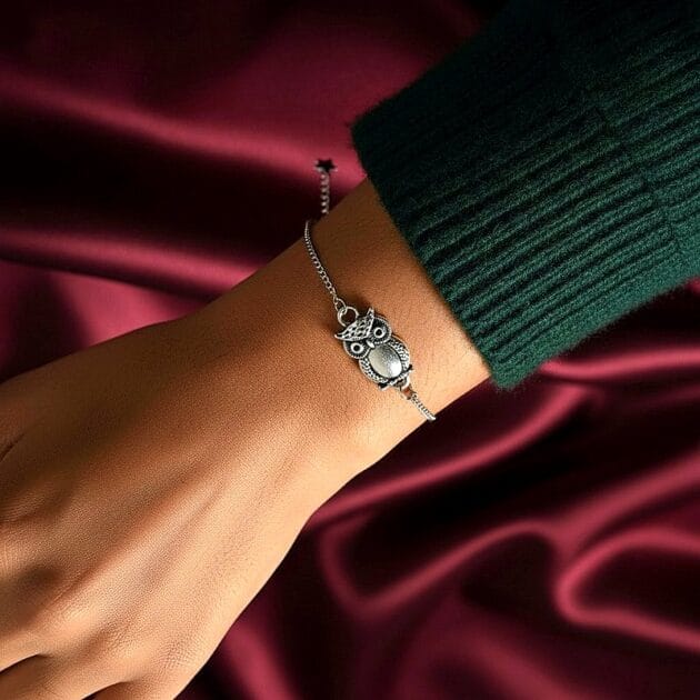 أسوارة فضية بقلادة بومة مفرغة على معصم امرأة