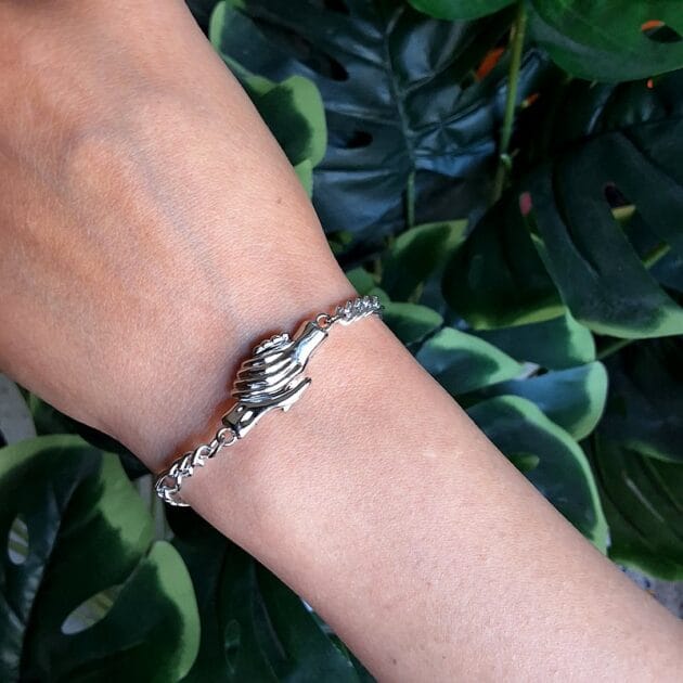 أسوارة فضية بتصميم يدين متشابكة مع قفل مغناطيسي.