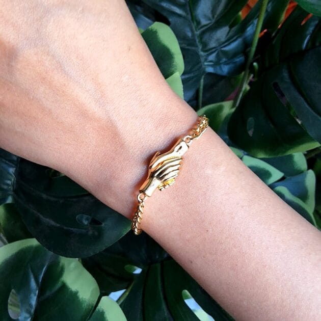 أسوارة ذهبية بتصميم يدين متشابكة مع قفل مغناطيسي.