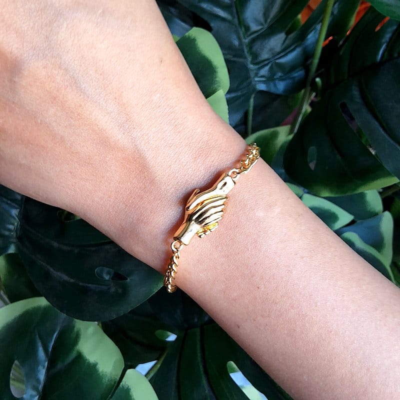 أسوارة ذهبية بتصميم يدين متشابكة مع قفل مغناطيسي.